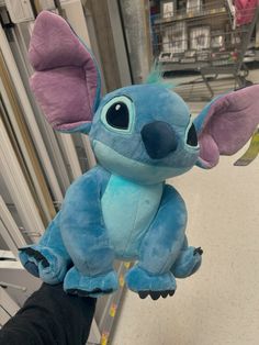 a blue stuffed animal with big ears on it's head is being held by someone