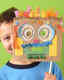 a young boy holding up a cardboard cut out of a monster mask with buttons on it