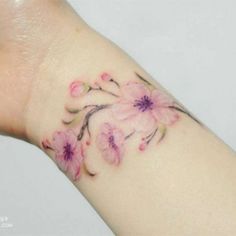 a small pink flower tattoo on the wrist