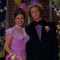 the young man and woman are posing for a picture in front of balloons, flowers and streamers