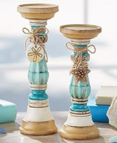 two wooden candlesticks are decorated with seashells and twine bow ties