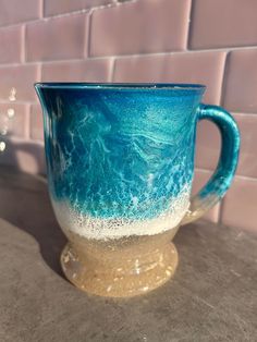 a blue and white mug sitting on top of a counter next to a brick wall