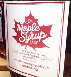 a bottle of maple syrup sitting on top of a table next to a sign that says maple syrup lady