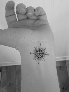 a small compass tattoo on the left inner forearm and wrist is shown in black and white