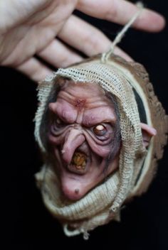 a creepy doll being held by someone's hand with it's mouth open