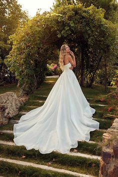 a woman in a white wedding dress standing on some steps with her back to the camera