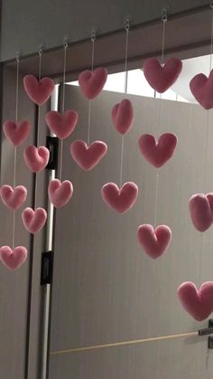 some pink hearts hanging from strings in front of a mirror