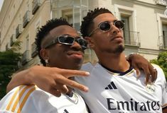 two young men standing next to each other in front of a building and pointing at something