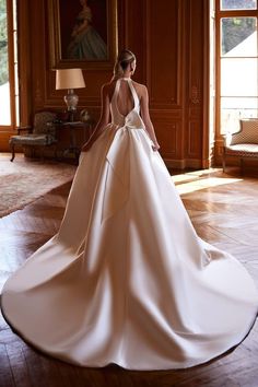 a woman in a wedding dress is standing on the floor with her back to the camera