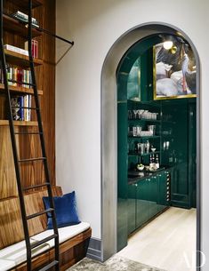 an arched doorway leading to a living room with green walls and wood flooring, along with bookshelves