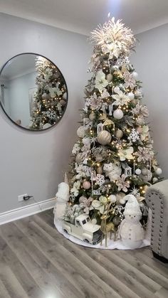 a decorated christmas tree in the corner of a room with a mirror on the wall