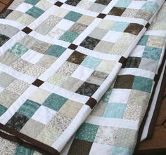 a quilt is laying on the floor next to a tablecloth with brown and white squares