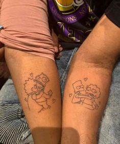 two people sitting next to each other with matching tattoos on their legs, one has a cartoon character and the other has a heart