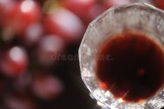 a wine glass filled with red wine and some grapes in the background royalty images, stock photos