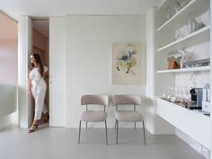 a woman in a white room with two chairs