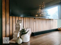 a wooden table topped with white pumpkins next to a flat screen tv mounted on a wall