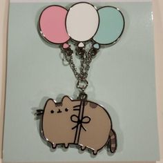 a key chain with a cat and balloons on top of it, sitting on a card