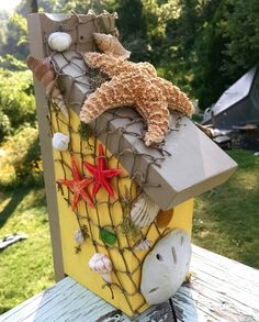 a birdhouse with sea shells and starfish on it