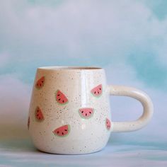 a ceramic mug with watermelon slices on it's side, sitting against a blue background