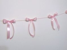 pink ribbon hanging from a clothes line on a white wall