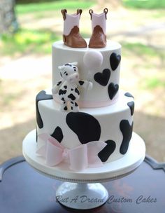 a three tiered cake decorated with black and white polka dots, pink bows, and boots