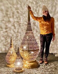 a woman standing next to three decorative lights