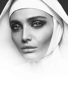 a woman with black eyes and white veil on her head is looking at the camera