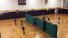 a group of people standing on top of a gym floor next to green dividers