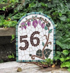 a small mosaic piece sitting on top of a wooden bench next to green leaves and ivy