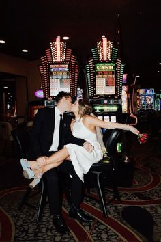 a man and woman kissing in front of slot machines