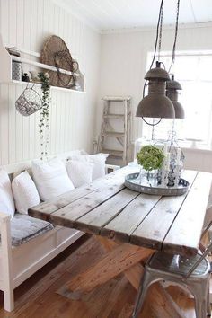 a wooden table sitting in the middle of a room next to a white couch and chair