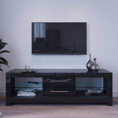 an entertainment center with a flat screen tv mounted on the wall and two vases in front of it