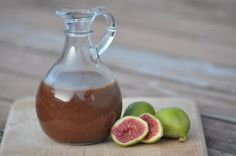 a glass jug filled with liquid next to figs on a cutting board