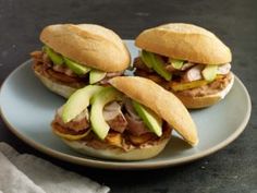 three sandwiches with meat and avocado on a plate