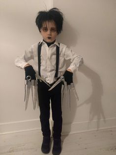 a doll dressed up as a man with scissors in his hands and wearing a white shirt and black tie