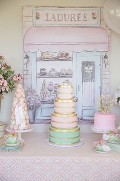 a table topped with cakes and flowers next to a wall mounted sign that says ladure