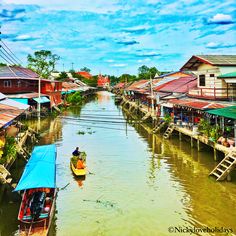 a river that has some boats in it and houses on the other side with green roofs