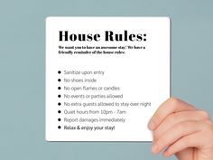 a person holding up a paper with the words house rules written on it in front of them