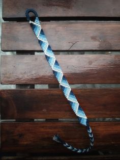 a blue and white rope on top of a wooden bench next to a black handle