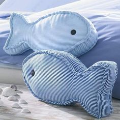 a blue and white fish pillow sitting on top of a bed next to seashells