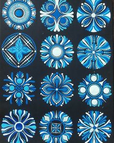 blue and white designs on black paper, with dots in the middle to make them look like they have been painted