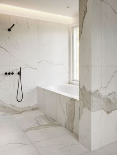 a bathroom with marble walls and flooring next to a bathtub in the corner