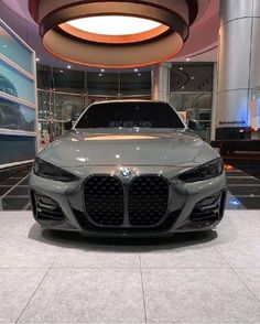 the front end of a gray bmw car on display at a showroom with large circular lights