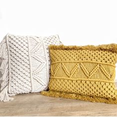 two knitted pillows sitting on top of a wooden table