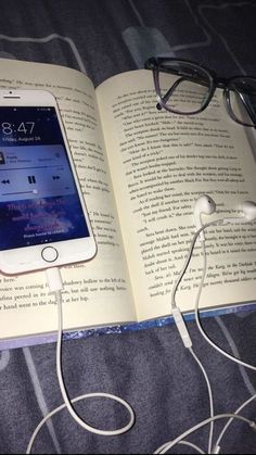 an open book with ear buds and headphones on it