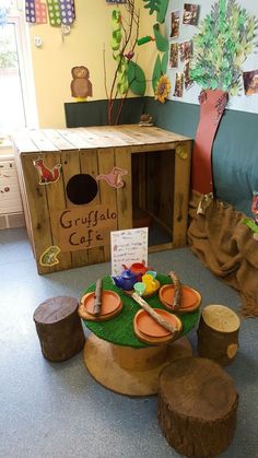 a child's play area with wooden benches and stools in the center, including a table made out of tree stumps