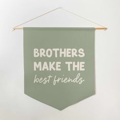 a green banner that says brothers make the best friends hanging from a clothes line on a wall