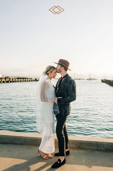 a man and woman standing next to each other near the water