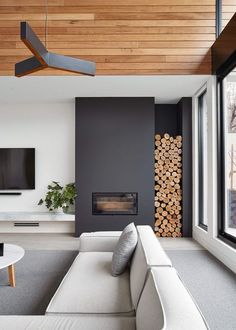 modern living room with white couches and wood paneled ceiling above the fire place