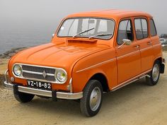 an orange car parked on top of a dirt road next to the ocean and water